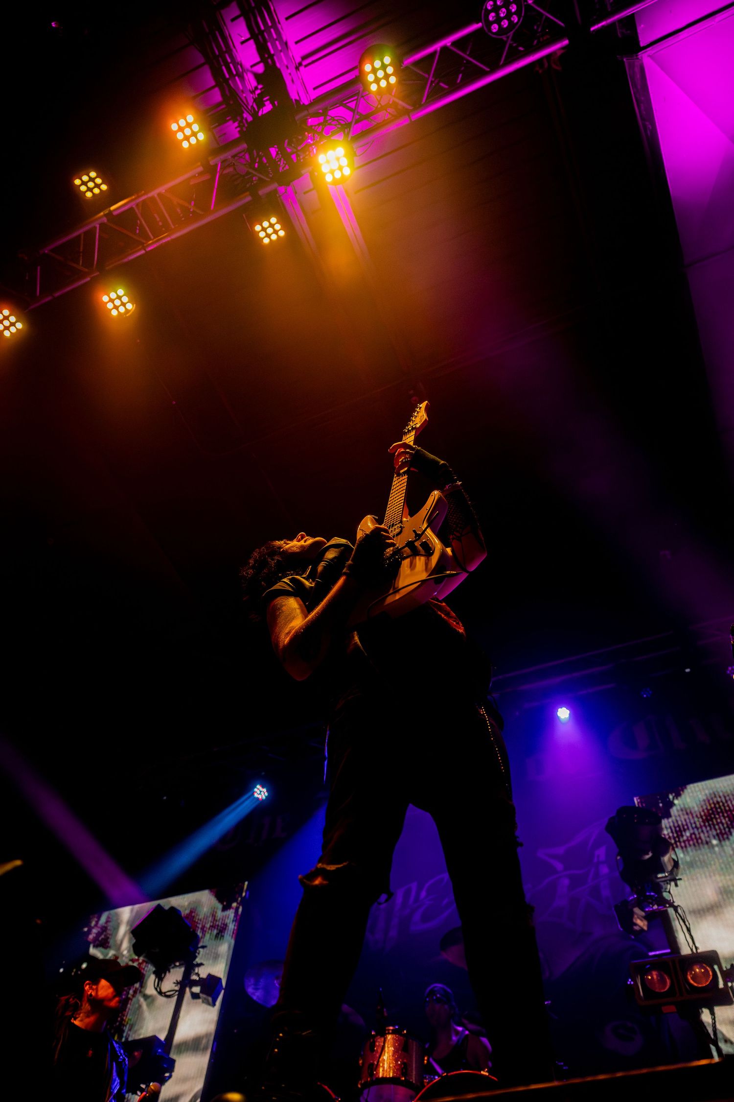 A silhouetted performer on stage with dramatic purple and orange lighting effects.