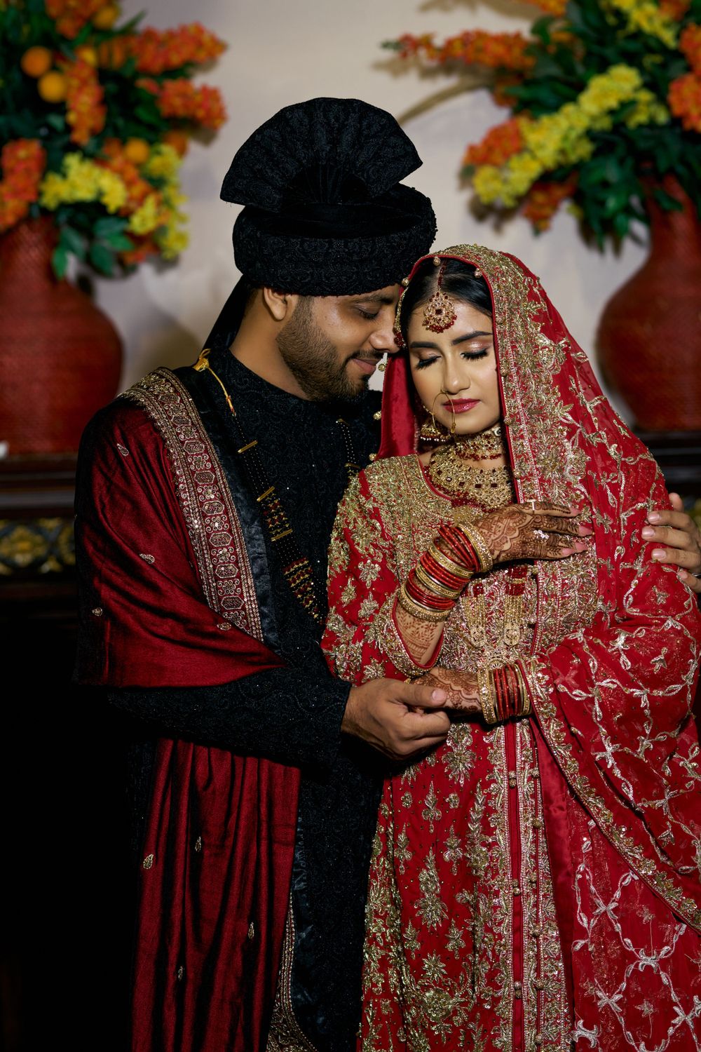 Intimate wedding moments captured in traditional South Asian wedding attire with rich red and gold details.