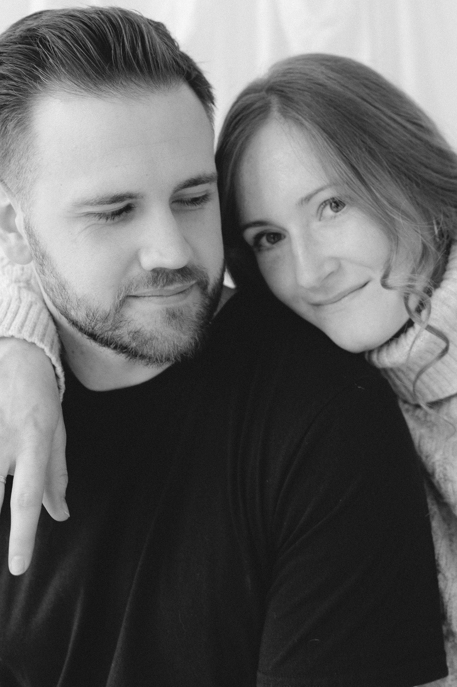 Black and white portrait photo of a couple in a tender moment showing affection and smiling together.