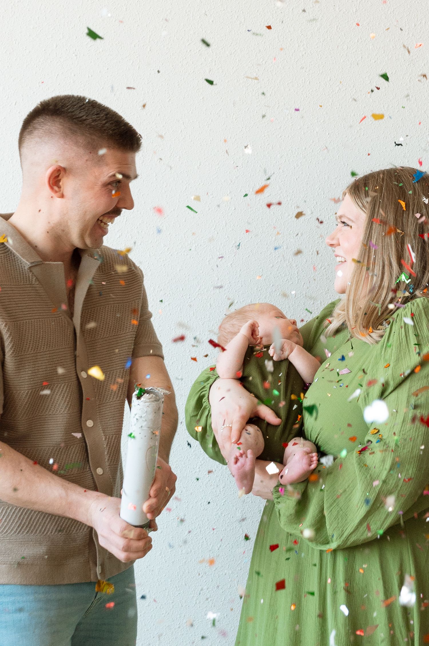 Happy couple celebrates with confetti and champagne popping in a joyful moment against white background.