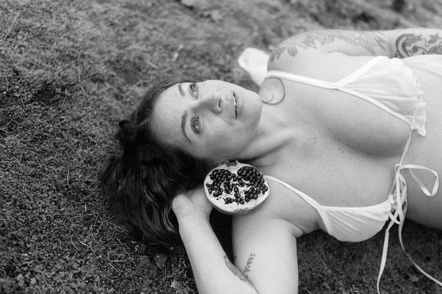 Black and white portrait with pomegranate in natural outdoor setting.