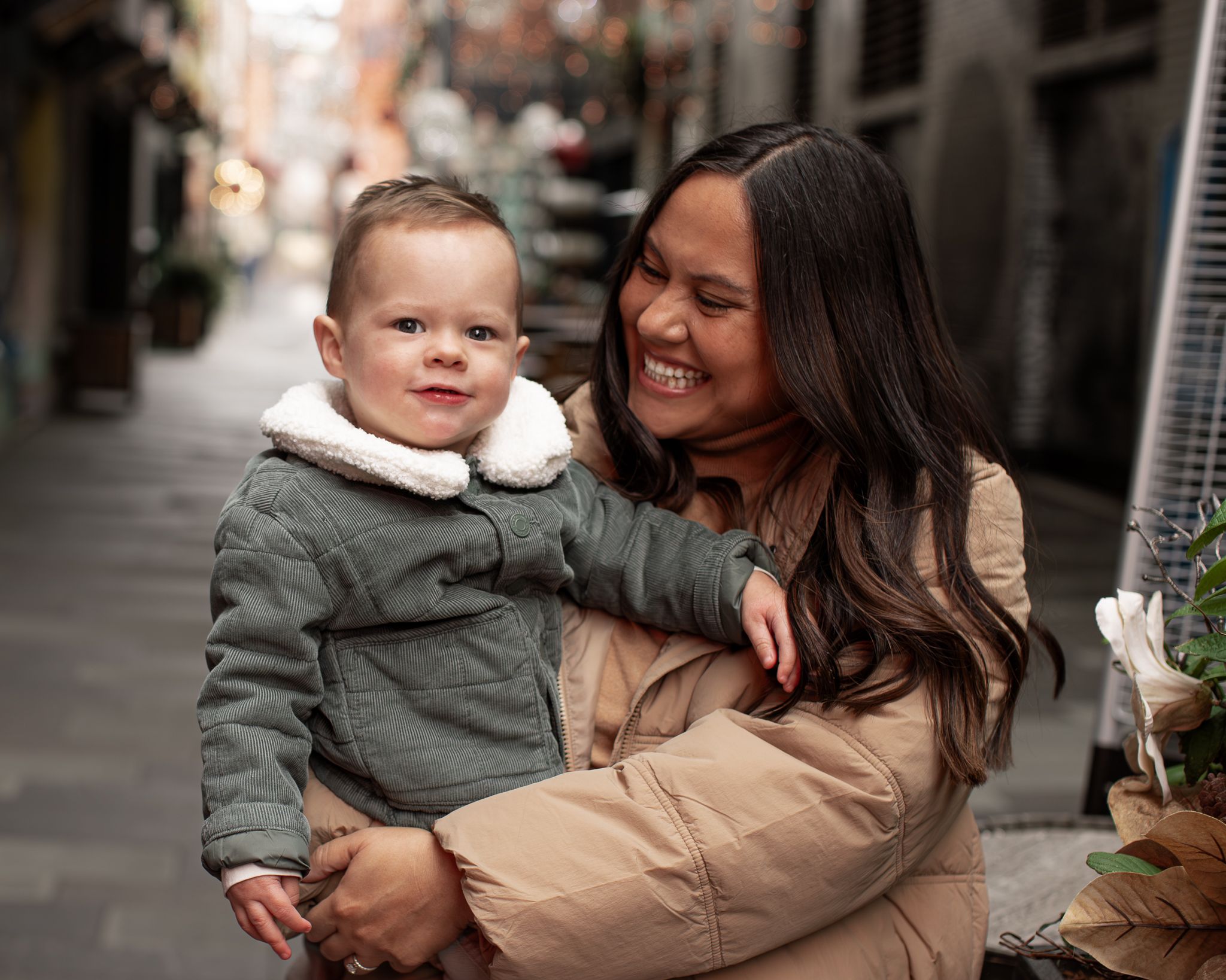 A family shares joyful moments together in a brick-lined shopping area decorated with twinkling lights.
