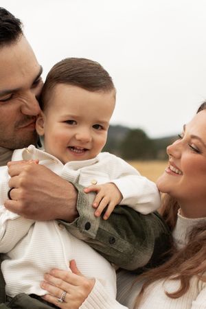 Loving family moment captured in soft natural lighting against rural backdrop.