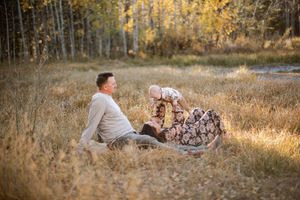 A family relaxing together on a blanket in a golden autumn field at sunset.