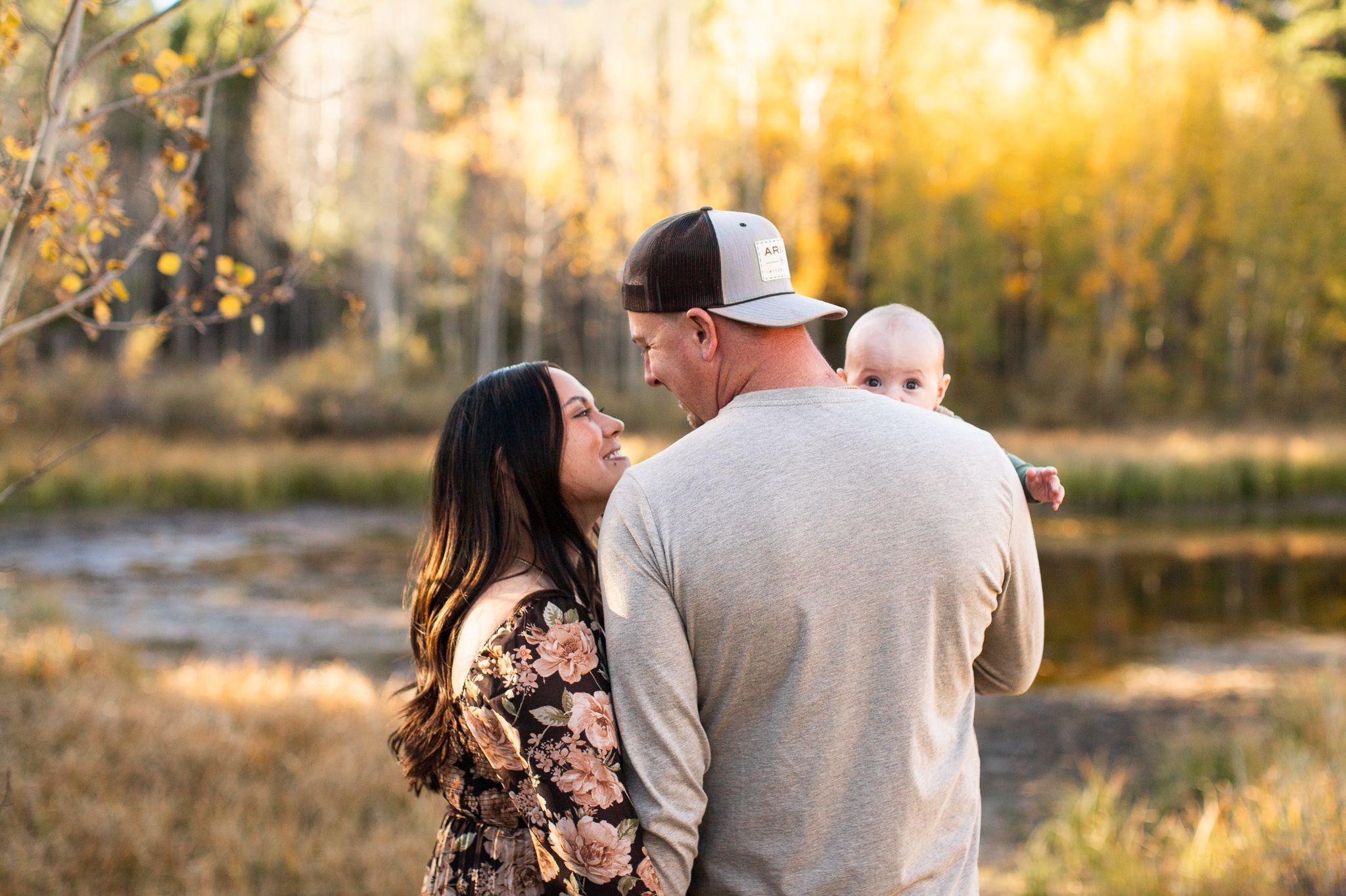 A family sharing an intimate moment outdoors with golden trees in the background.