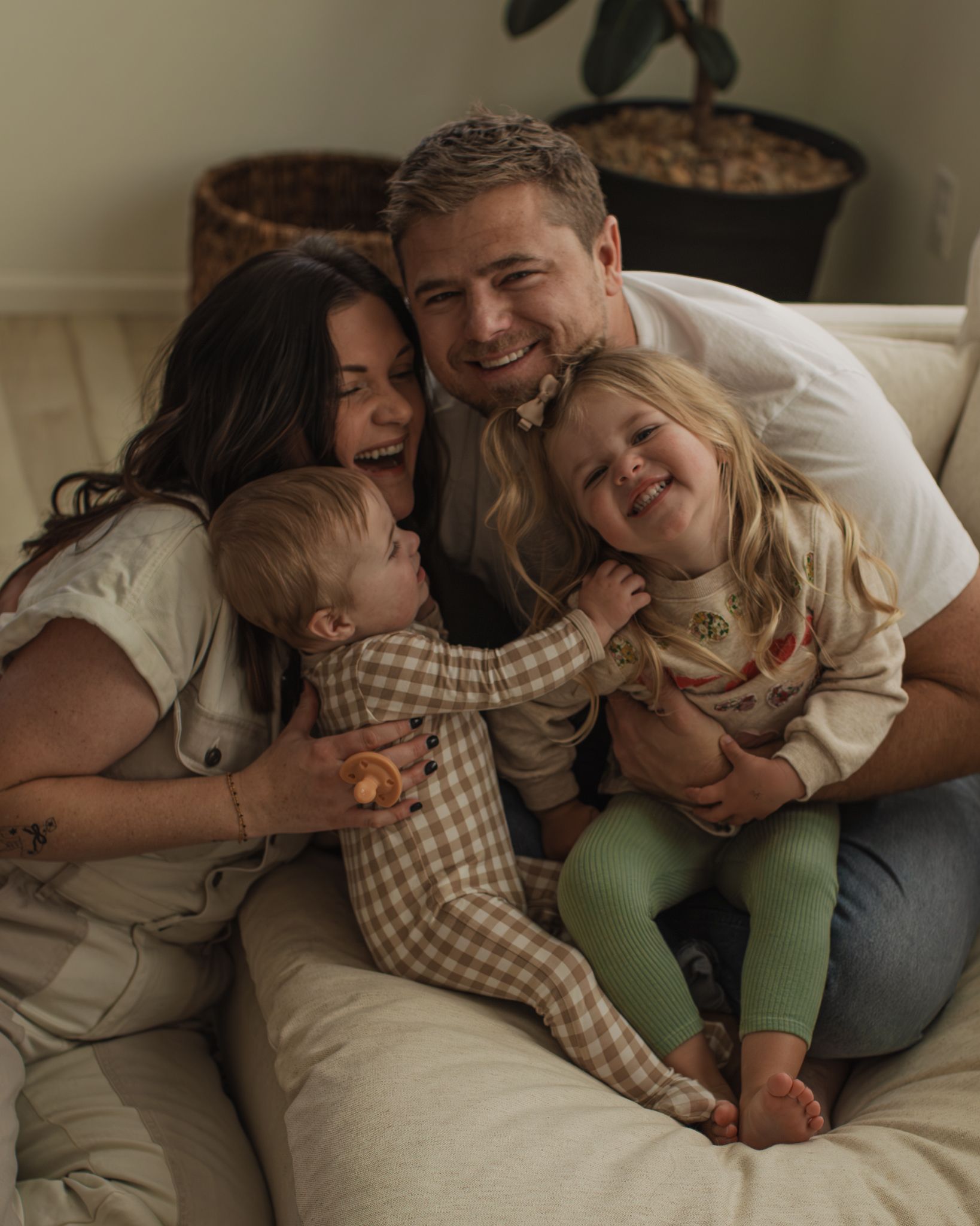 A family cuddles together while lying on a bed in a series of warm, intimate lifestyle photos.