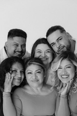 Black and white portrait of six smiling family members posing closely together against a white background.
