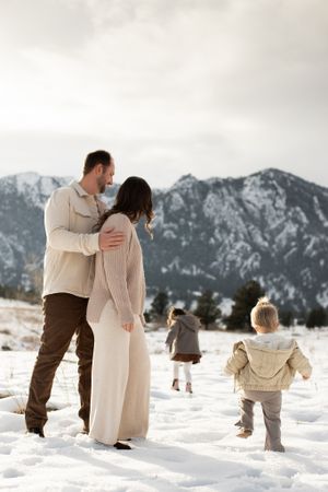 Family enjoying winter day with snowy mountains in background.