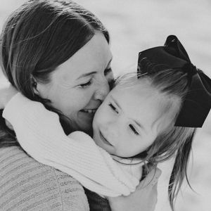 A tender black and white portrait of a parent and child sharing an intimate embrace and smile.