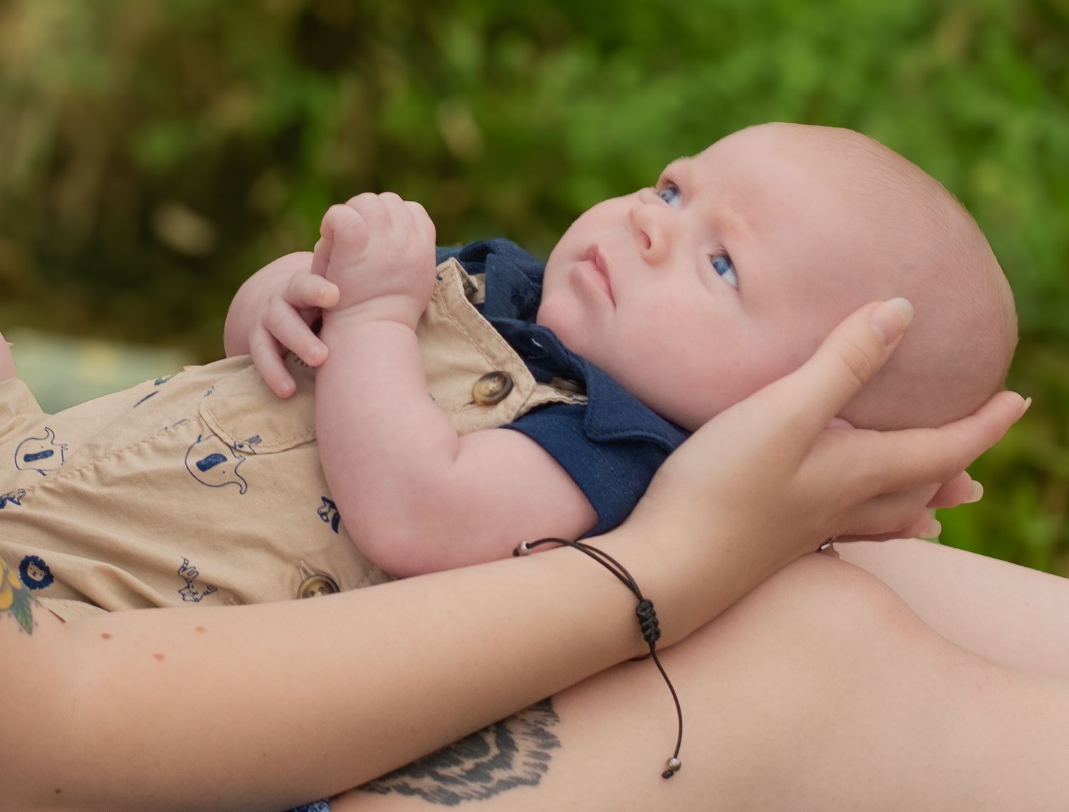 Close-up of a baby with bright blue eyes lying on their back outdoors.