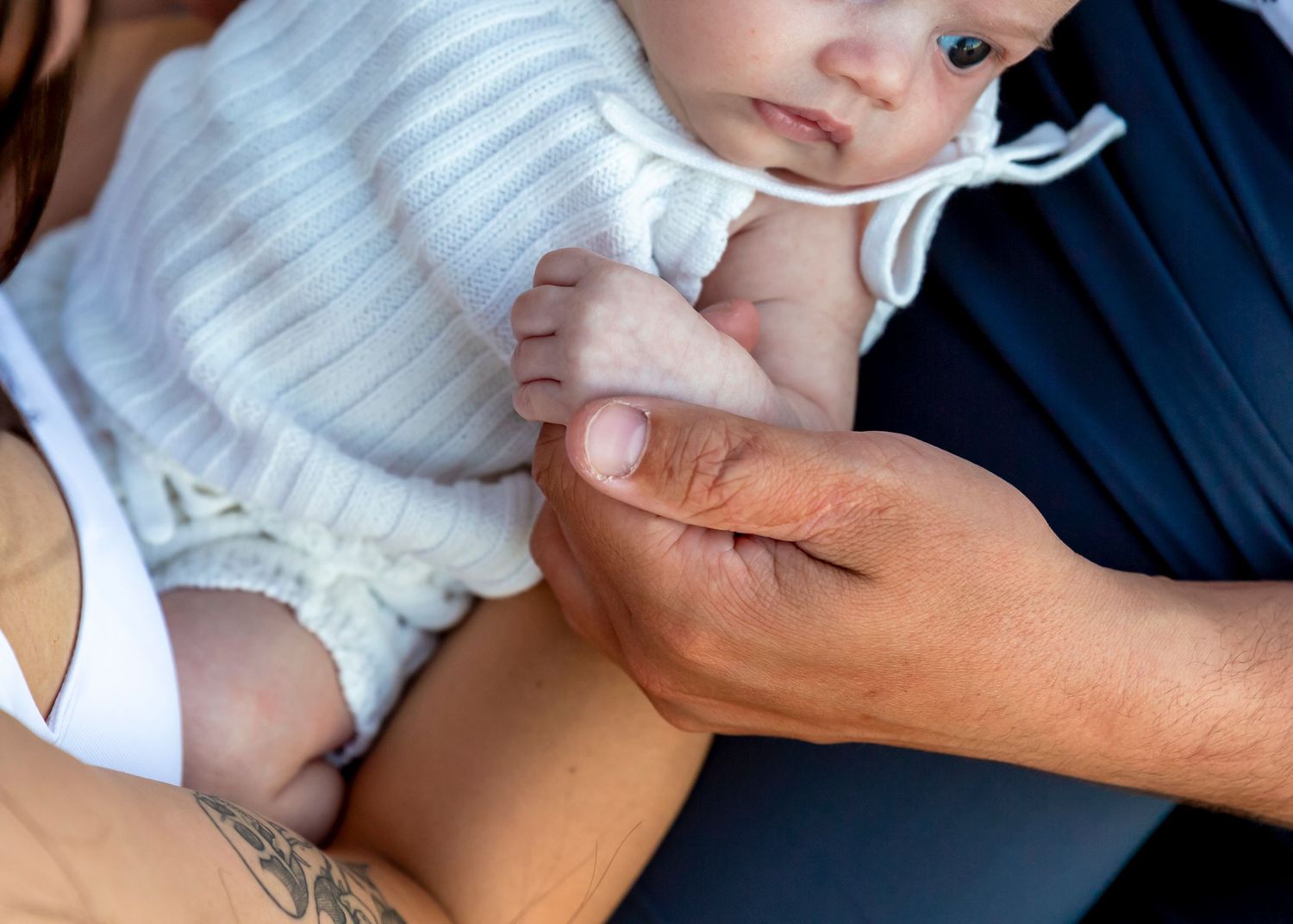 Natural newborn photo in Perth with baby held in parents’ arms, unposed and with no props or wraps.