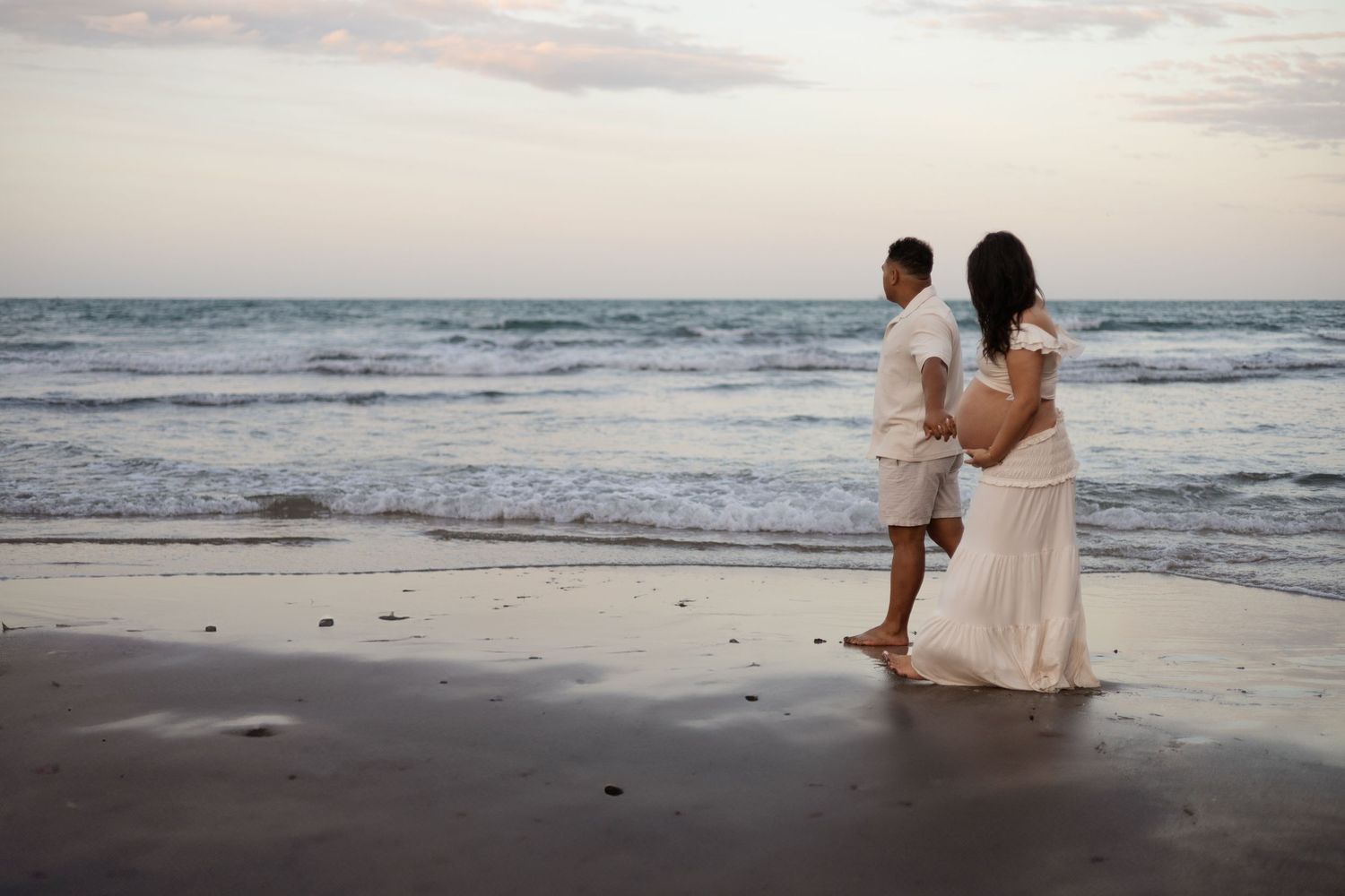 Couple walking along the beach at Taylor's Mistake during maternity session