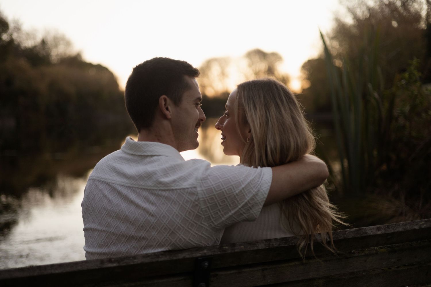 couple sitting on bench at sunset during couples session at The Groynes, Christchurch