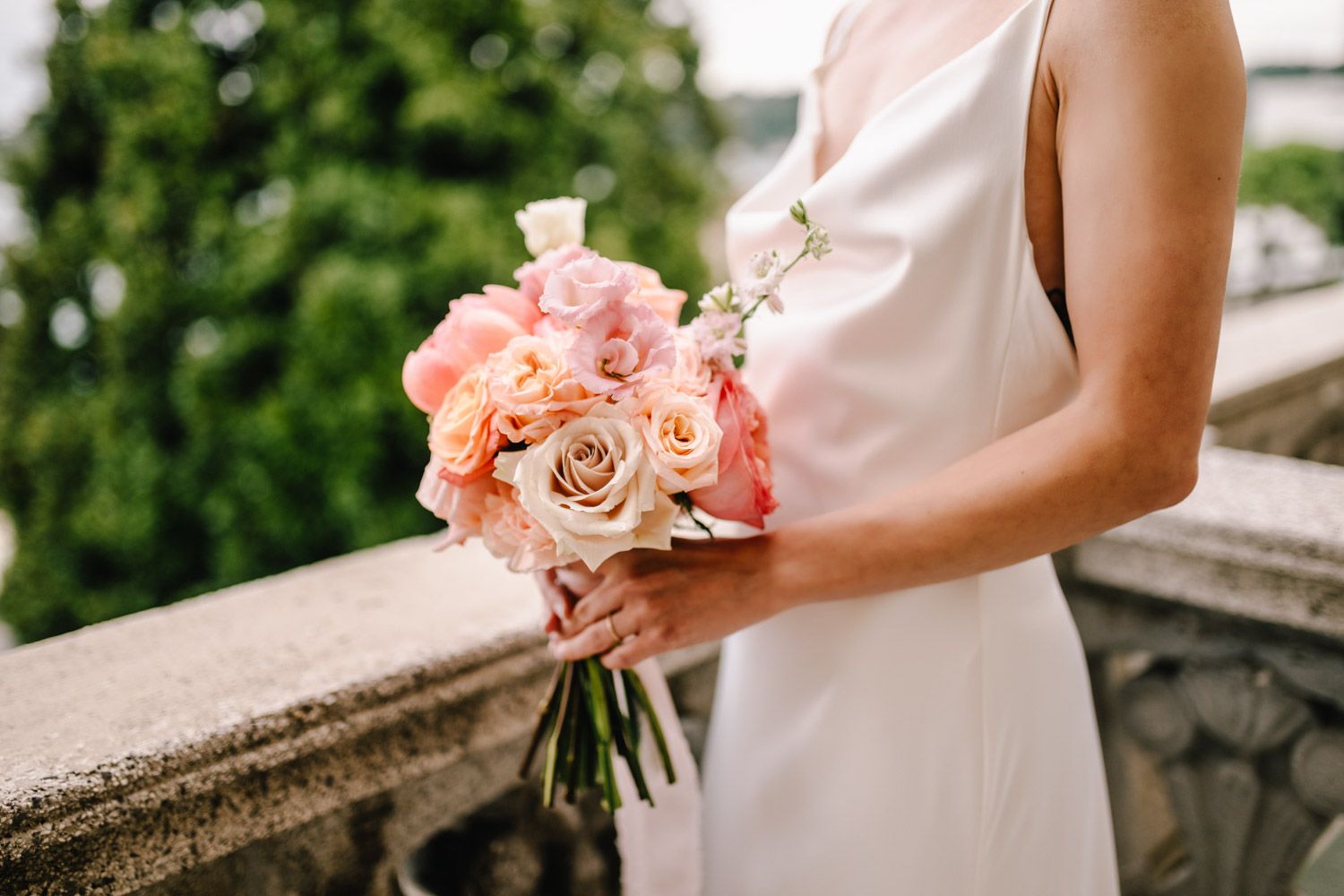 Close-up of a bridal bouquet with coral, pink, and peach roses for a spring elopement