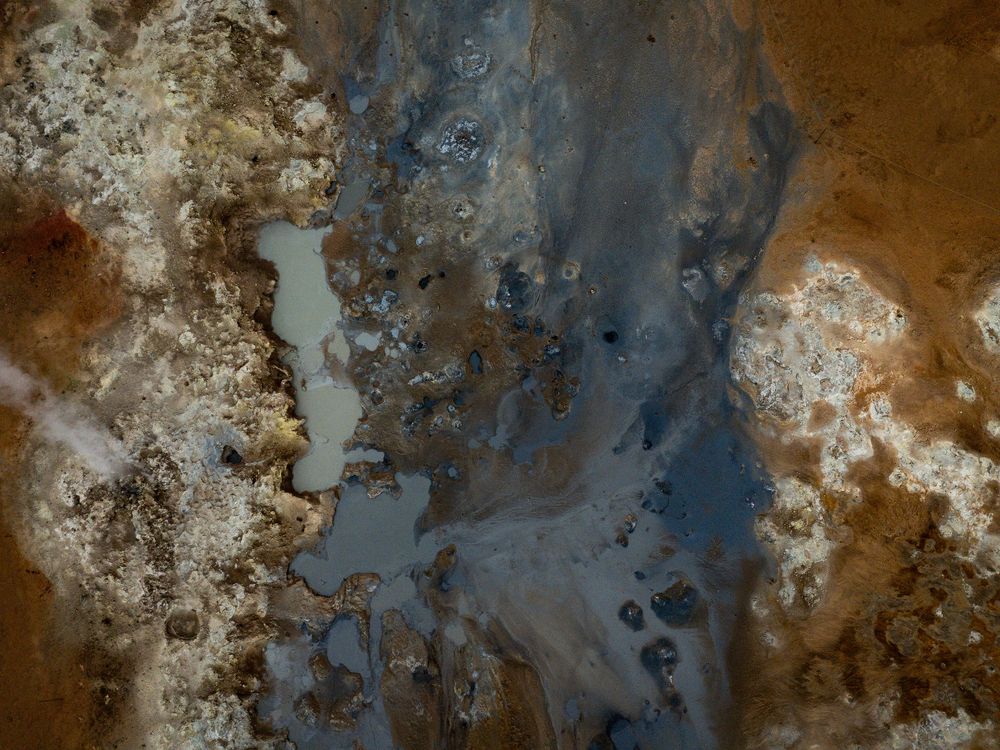 Abstract aerial view of rusty brown and blue mineral patterns in natural rock formations.