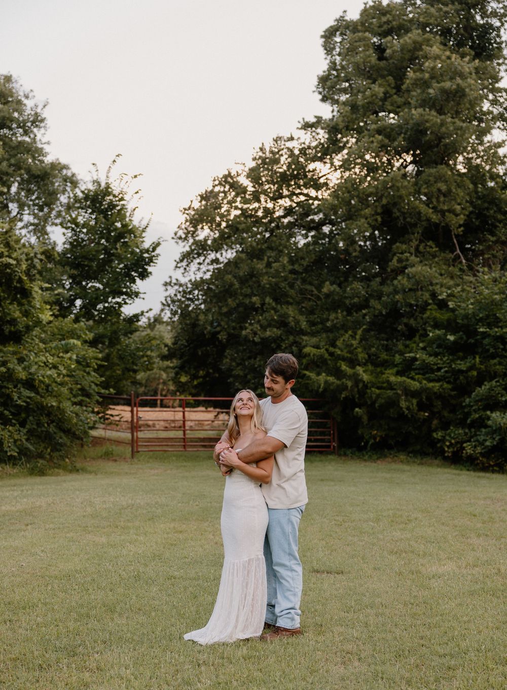 A couple shares an intimate moment while dancing together in a rustic field setting.
