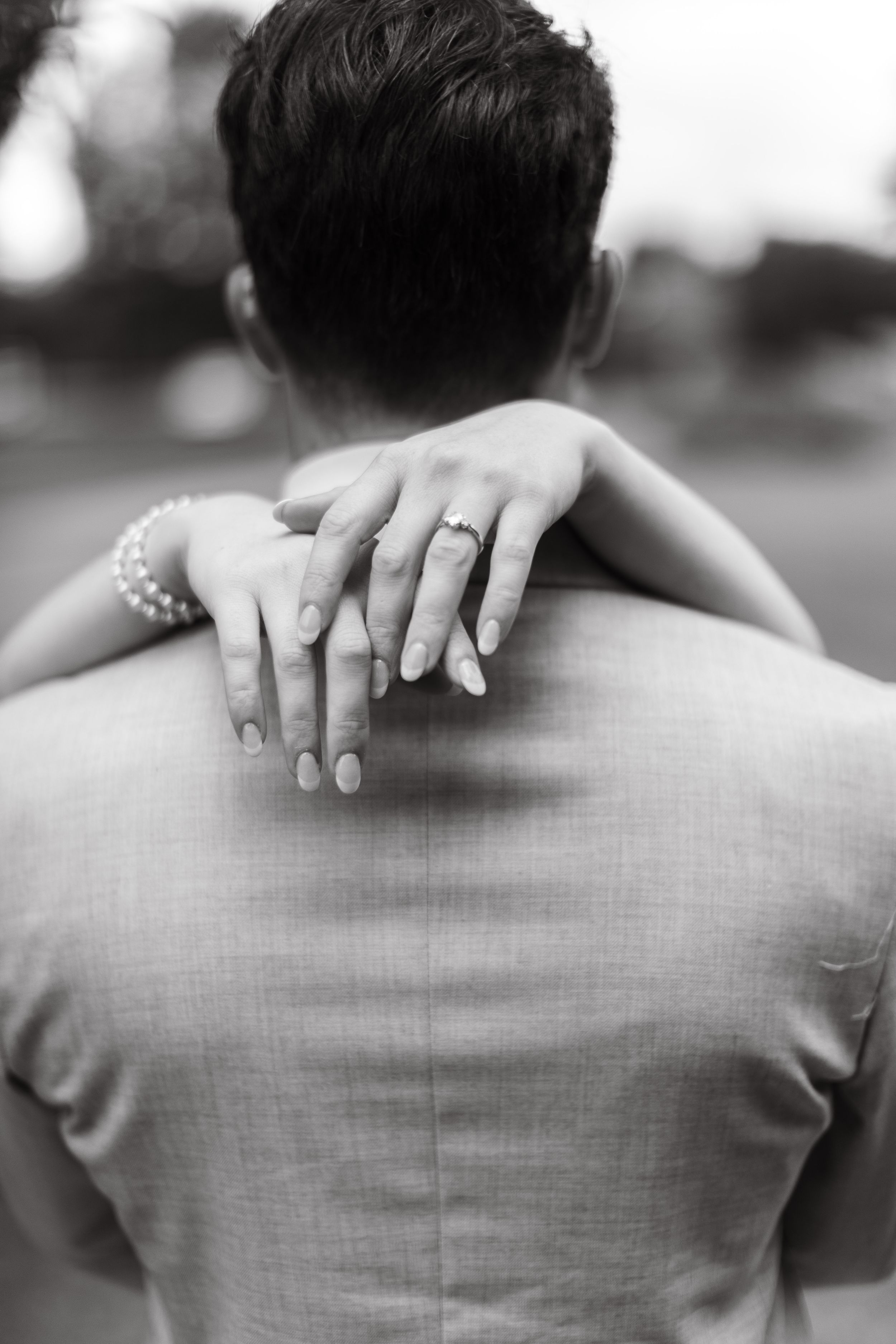 The image shows a couple embracing in a tender moment, with the man's hands on the woman's back.