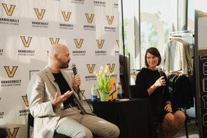 Two speakers engage in conversation at a Vanderbilt University event, seated before a branded backdrop.