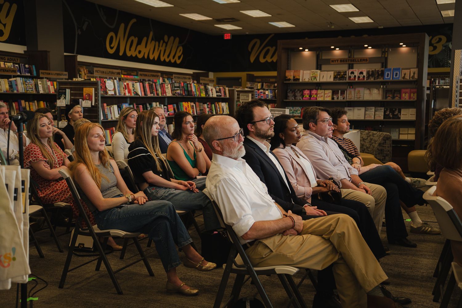 Audience seated in rows at a Nashville bookstore event, surrounded by shelves of books in warm ambient lighting.