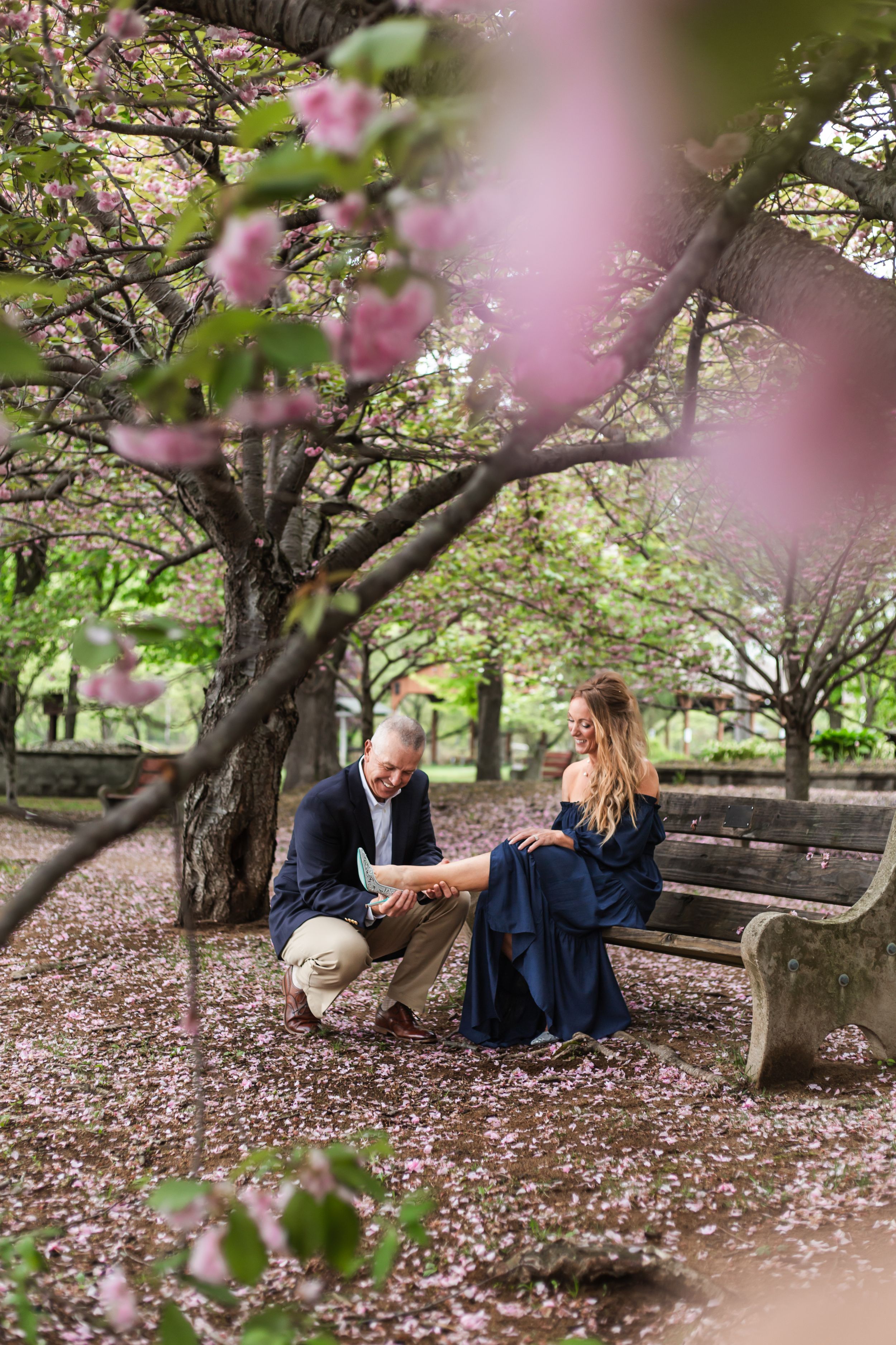 Couple sitting under blooming cherry blossom trees in a romantic spring setting.