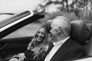 Candid moment of couple enjoying a drive in convertible car on sunny day.