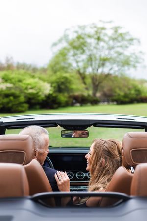 Interior view of a convertible car showing tan leather seats and dashboard with trees visible outside.