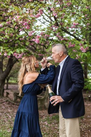 A couple shares a tender moment under blooming pink cherry blossom trees in springtime.