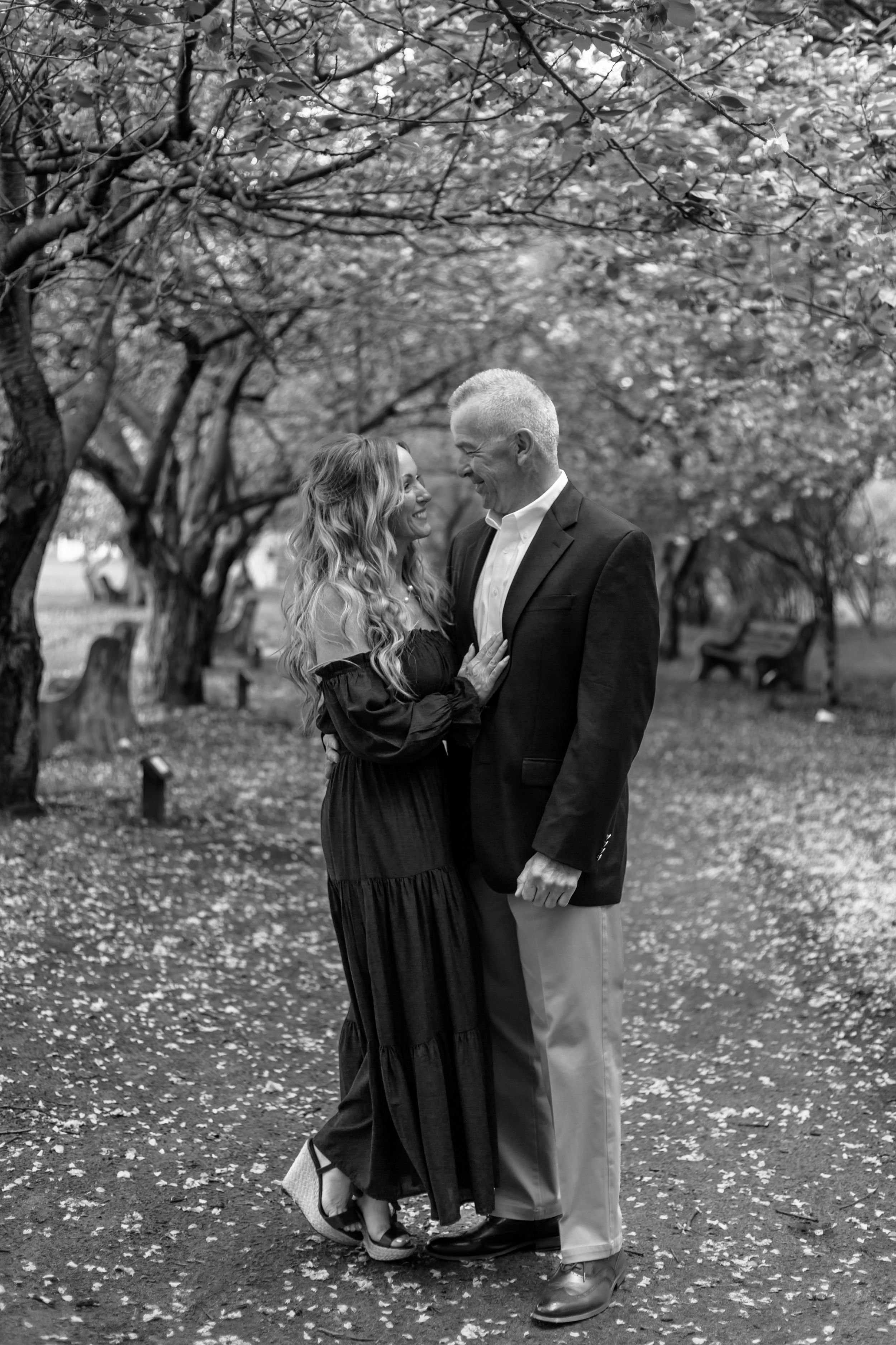 Black and white photo series showing a romantic moment under cherry blossom trees.