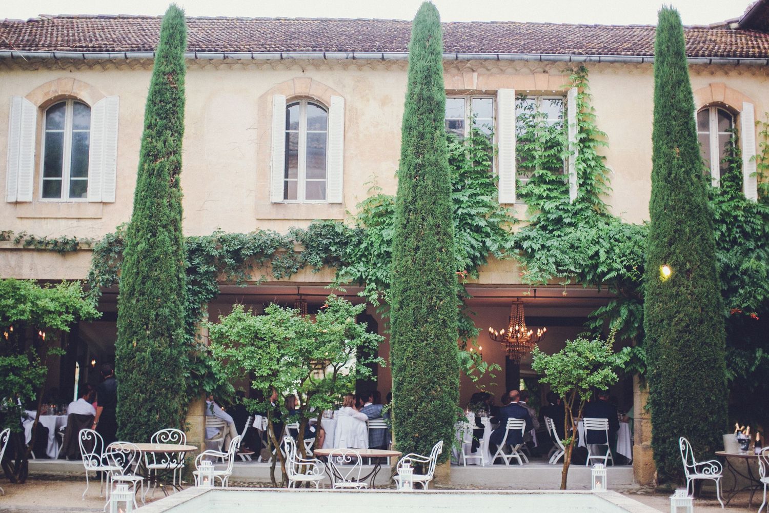 French chateau wedding courtyard with elegant outdoor reception setting, cypress trees, classic architecture in a refined destination atmo