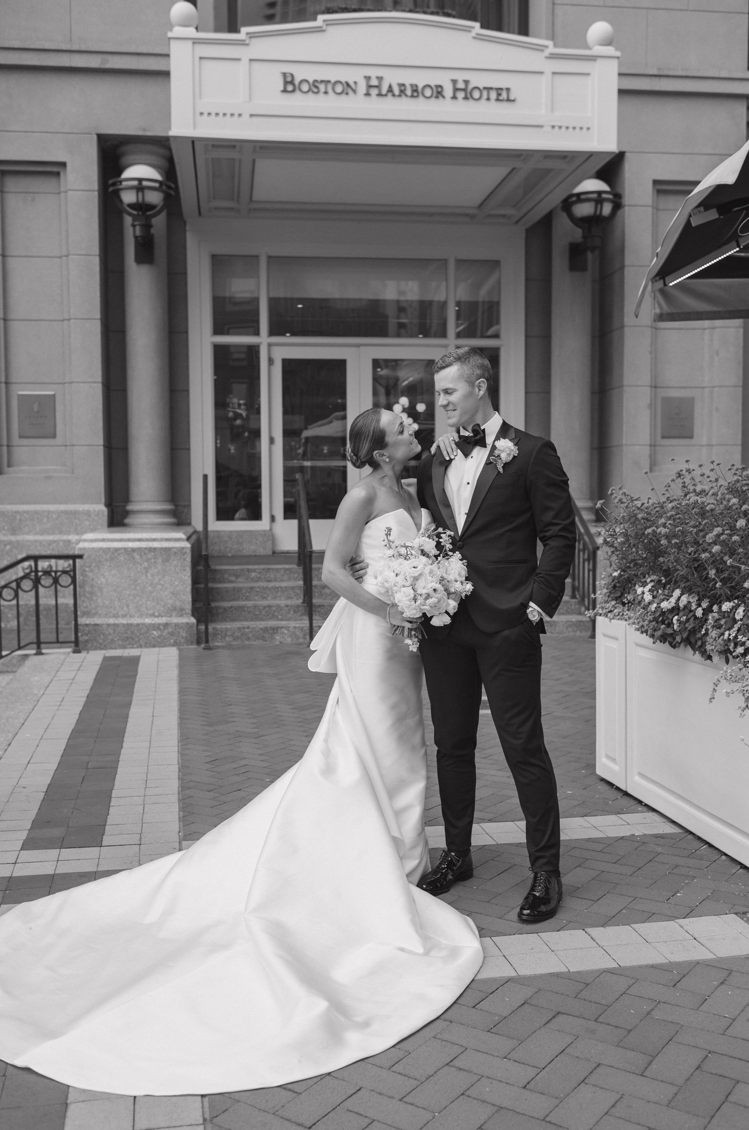 Bride and groom share romantic moments in front of the Boston Harbor Hotel entrance during their wedding photoshoot.