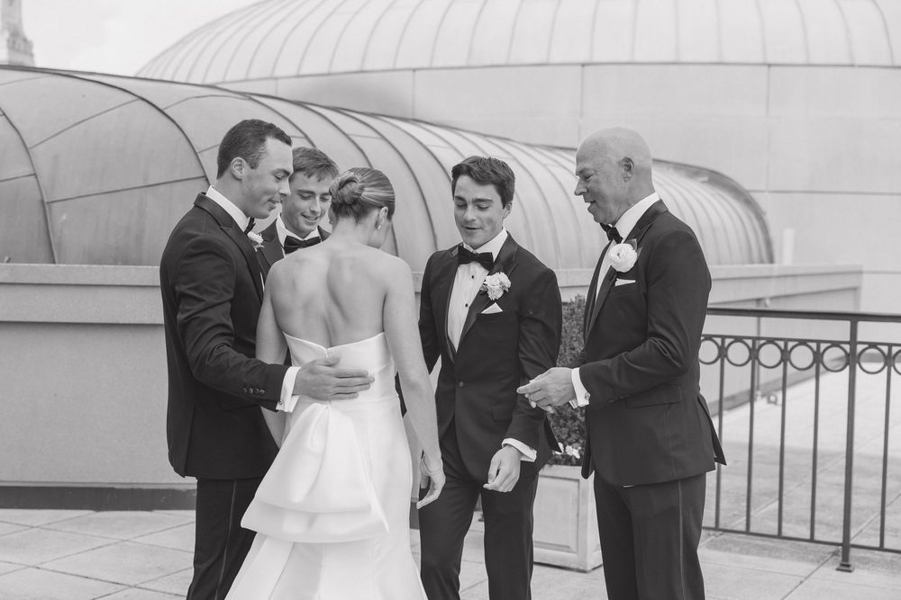 A wedding ceremony takes place under a white gazebo with guests gathered to witness the special moment.