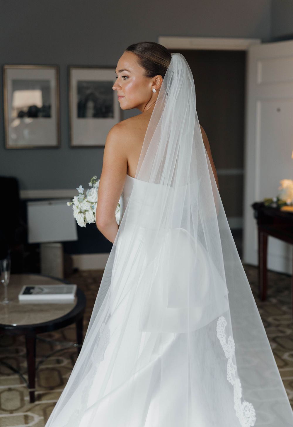 A flowing white cathedral length wedding veil with delicate lace details trails elegantly behind the bride.