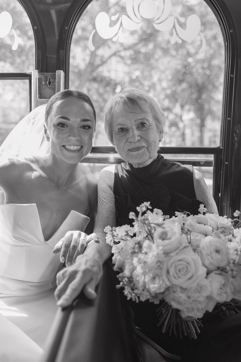 Black and white wedding photos show joyful moments between a bride and elderly family member in a car with white floral bouquet.
