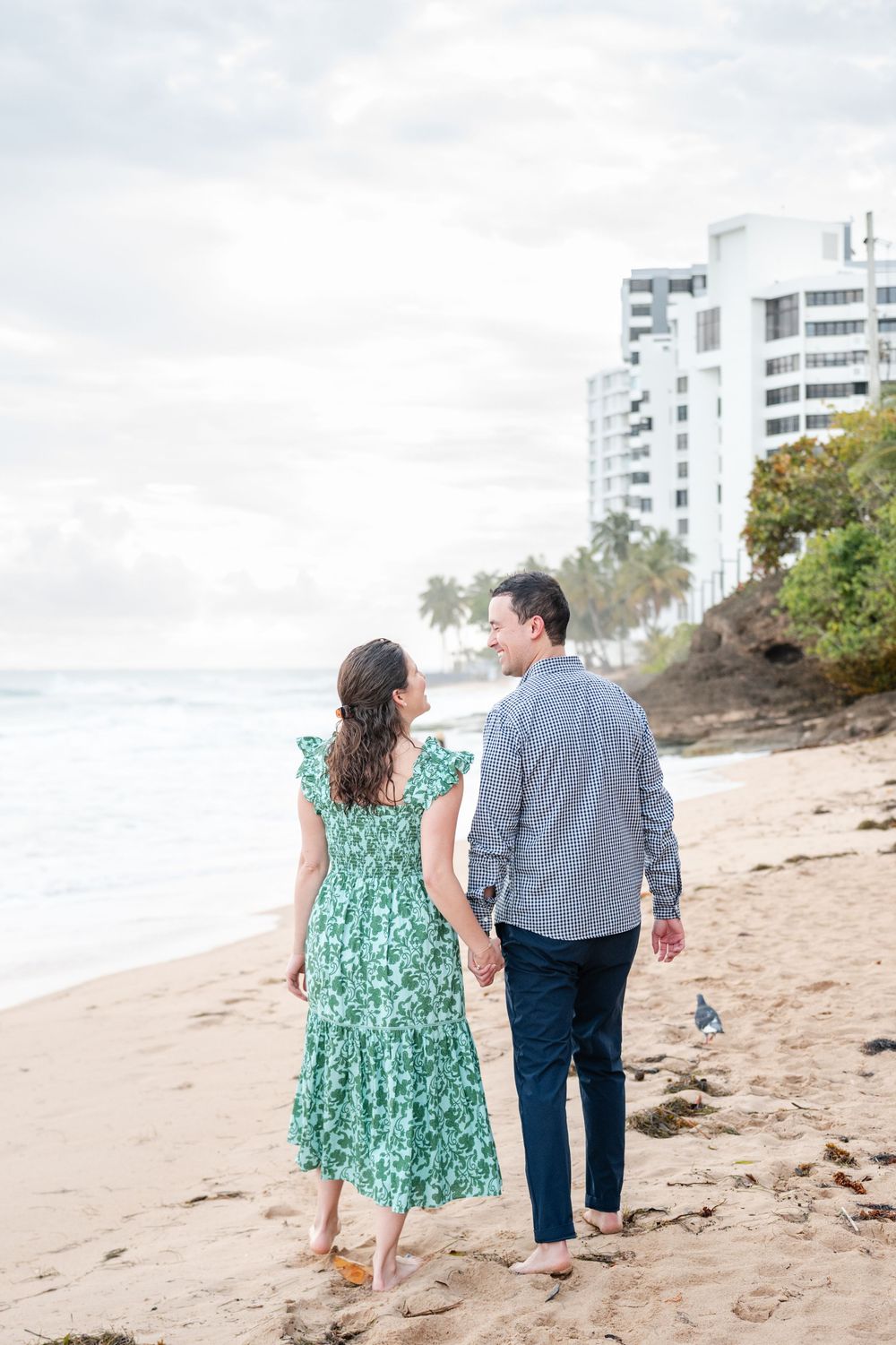 Couple walking along beach with ocean view during engagement session in Condado San Juan Puerto Rico