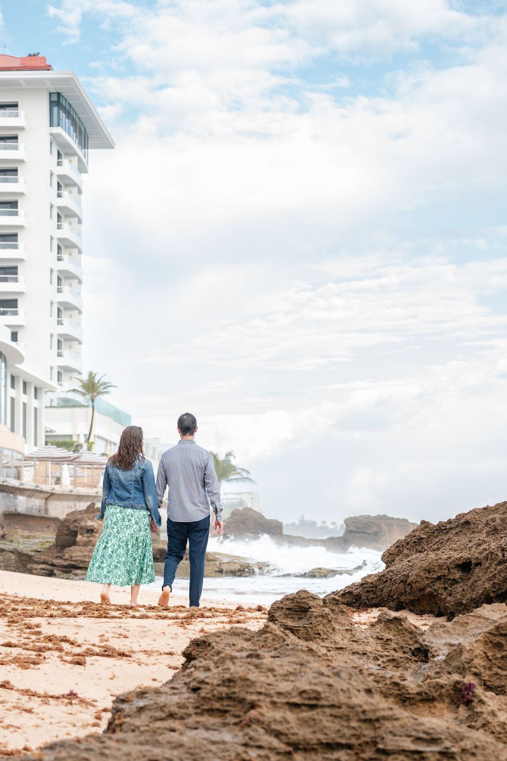 Couple walking along rocks with ocean view during engagement session in San Juan Puerto Rico