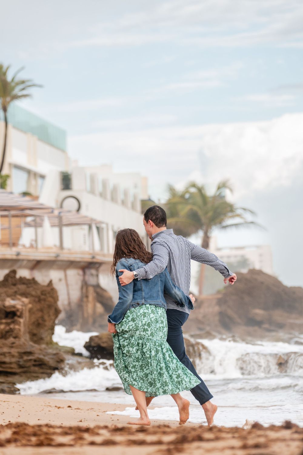 Couple walking playfully along beach during engagement session at Condado Beach San Juan