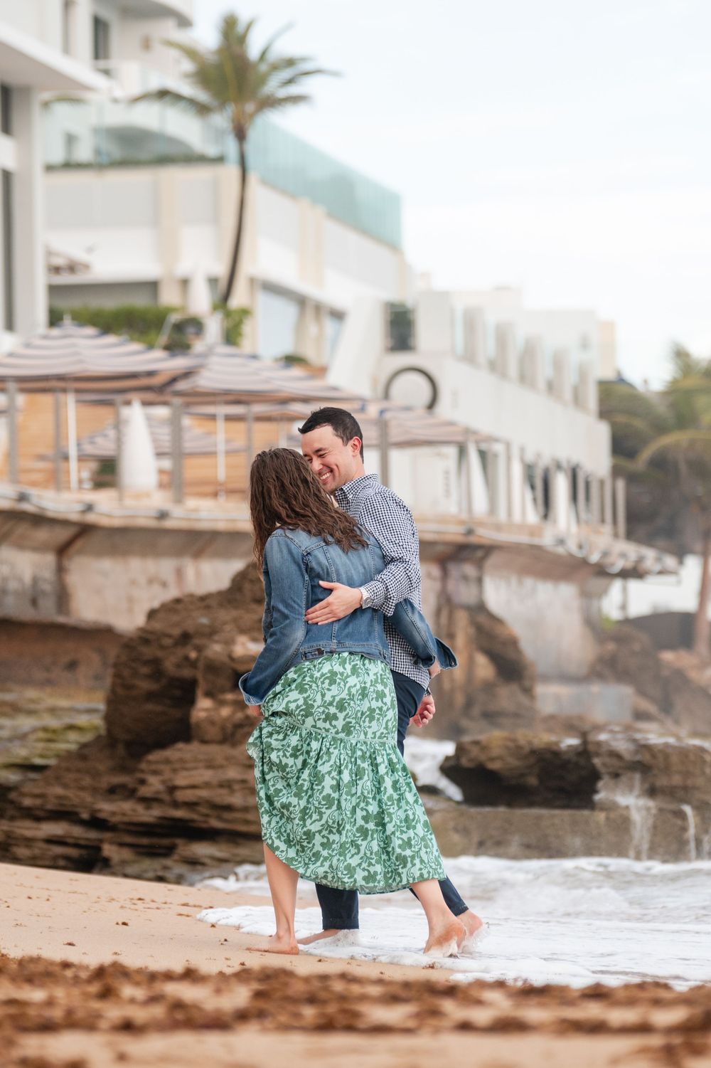 Couple embracing near beachfront buildings during engagement session in Condado San Juan Puerto Rico