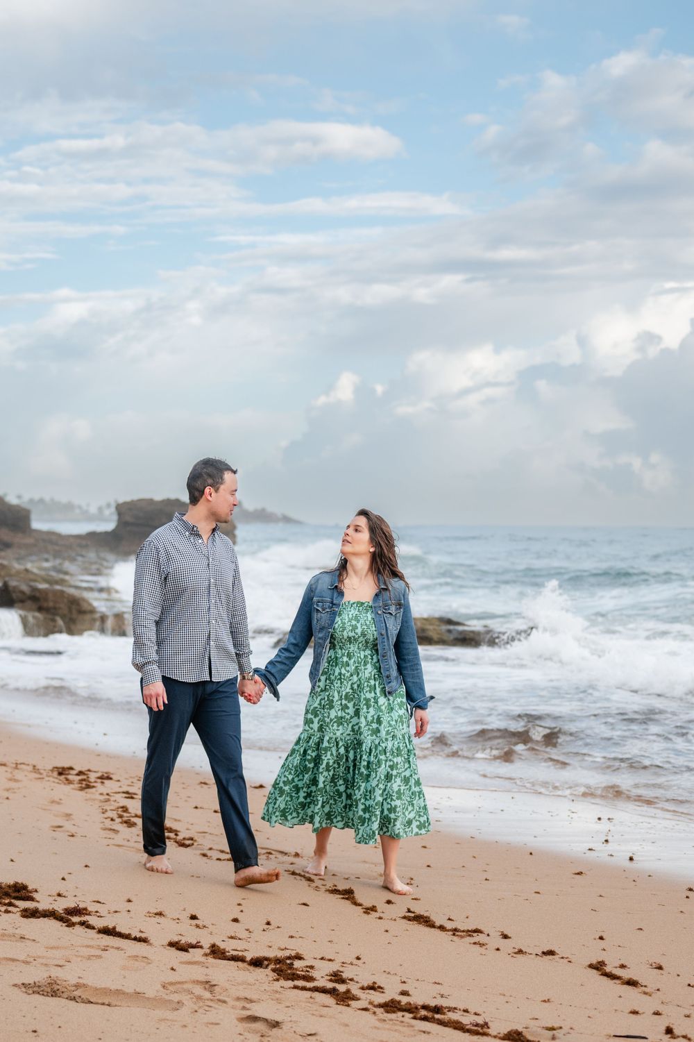 Couple walking along shoreline holding hands during engagement photos in Condado Beach Puerto Rico