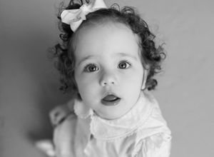 A series of black and white photographs showing a young child with curly hair in different expressions and poses.