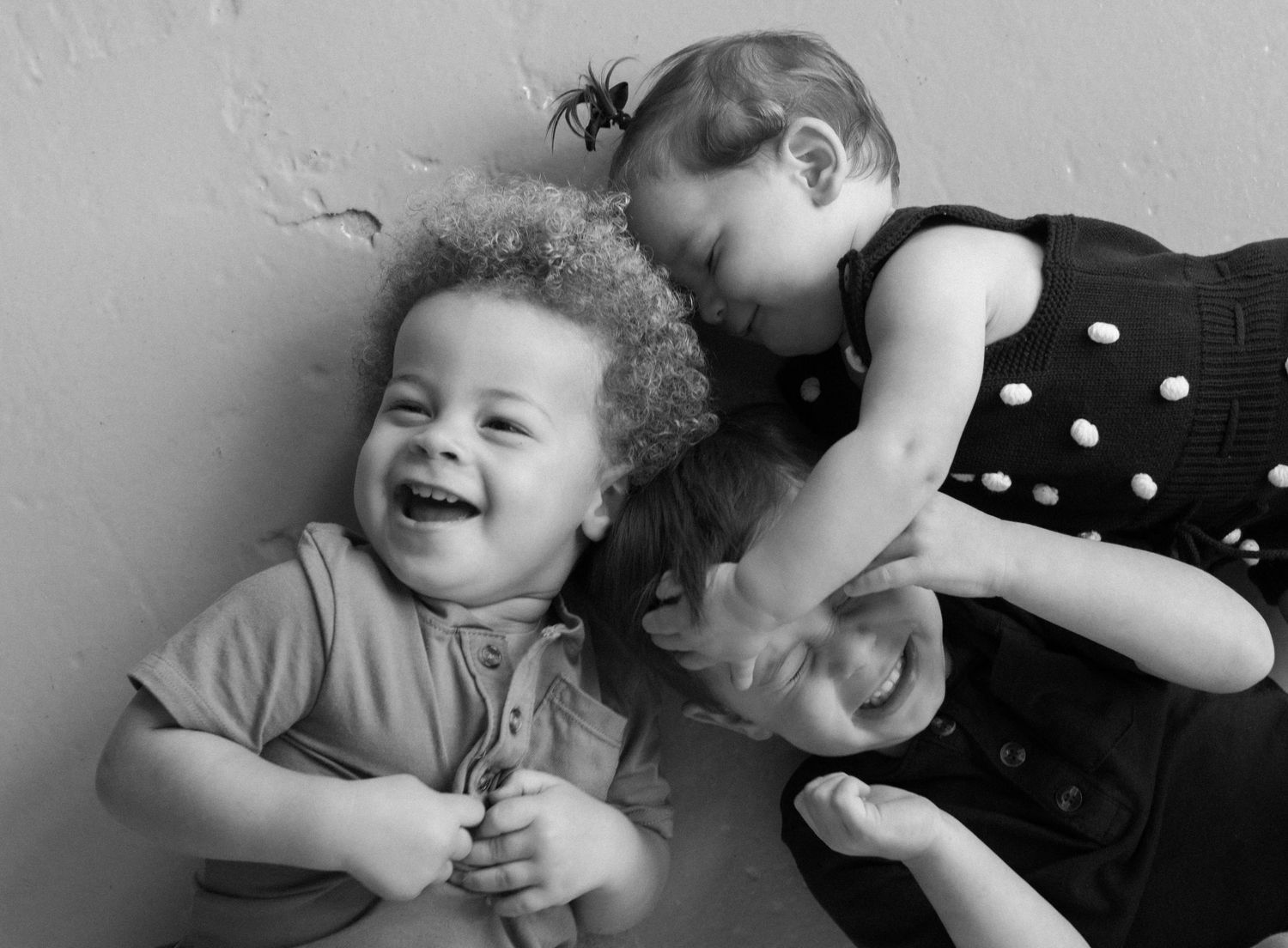 A heartwarming sequence of black and white photos showing playful moments between a parent and child laughing together.