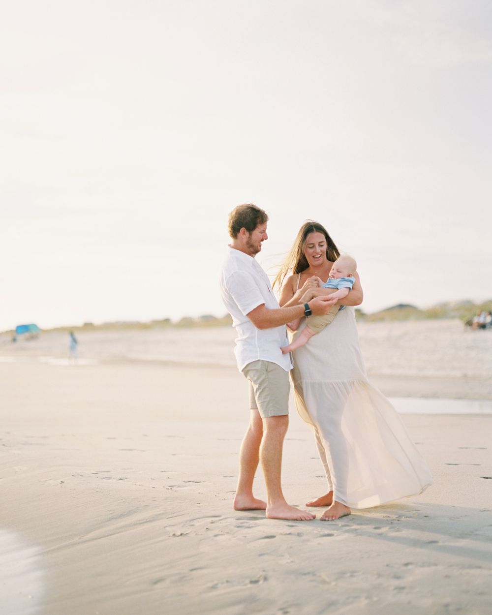 A couple shares a romantic moment on a serene sandy beach during a sunset photoshoot.