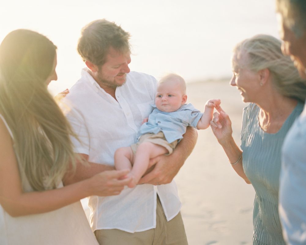 A series of soft, light-filled family moments showing parents interacting with a baby in white clothing.
