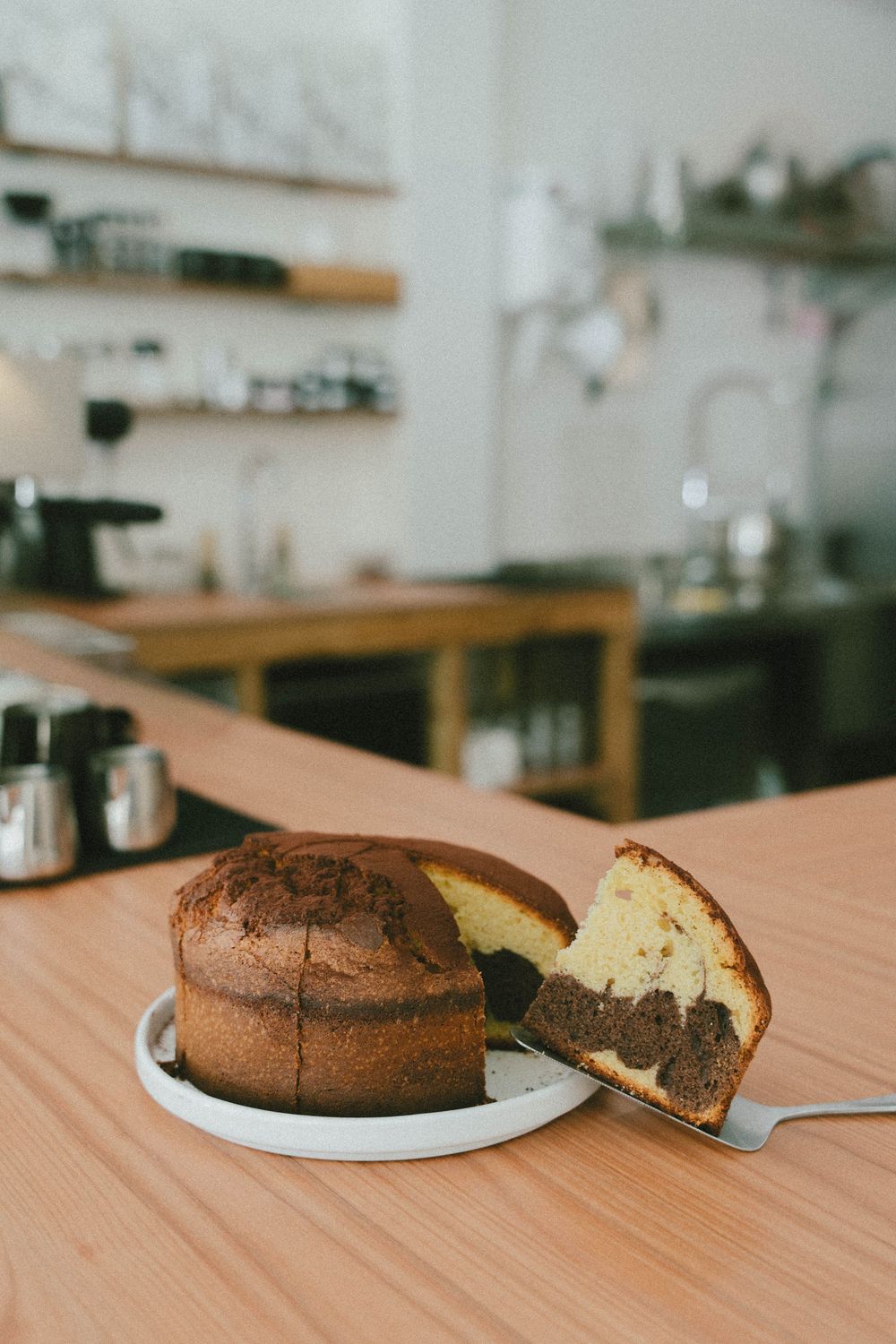 Gâteau en marbre tranché sur assiette blanche affiché sur un comptoir en bois dans un cadre de café confortable.
