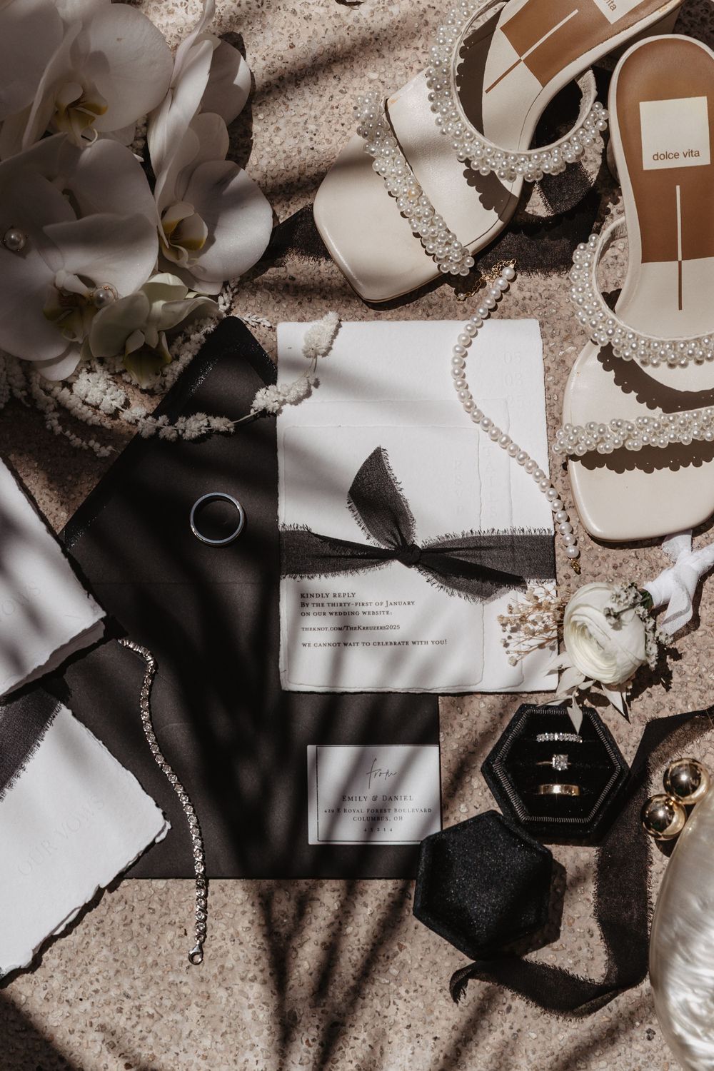Moody flatlay of wedding details including rings, invitations, and delicate lace in sepia and neutral tones.