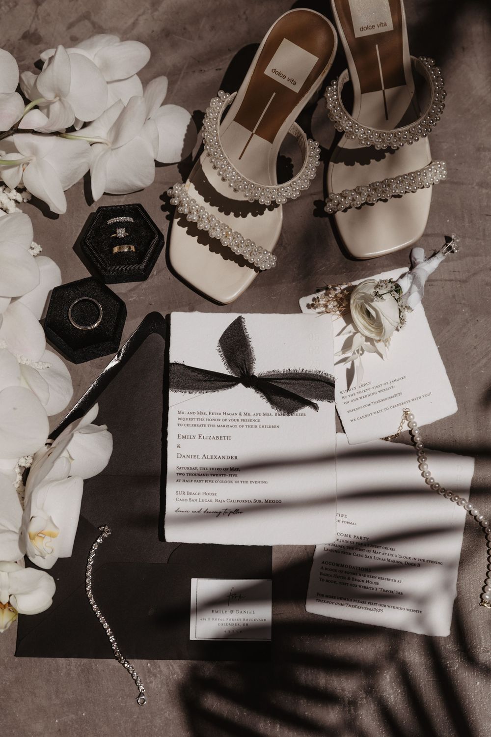 Wedding accessories including elegant shoes, jewelry, and invitation cards arranged artistically in black and white tones.