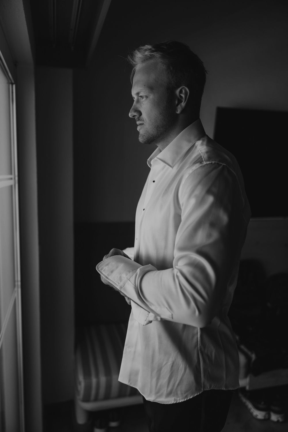 A series of black and white photographs showing someone in a white shirt standing by a window in dramatic lighting.