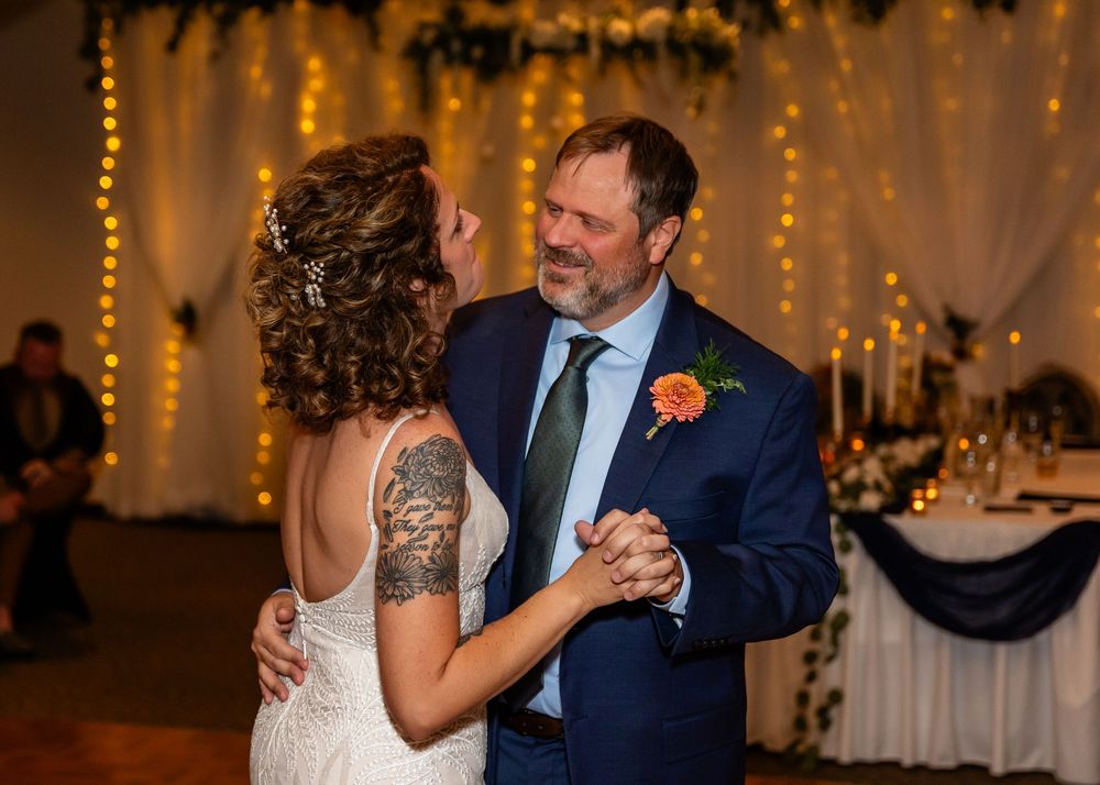 Bride and groom sharing their first dance at a wedding reception with fairy lights in the background.