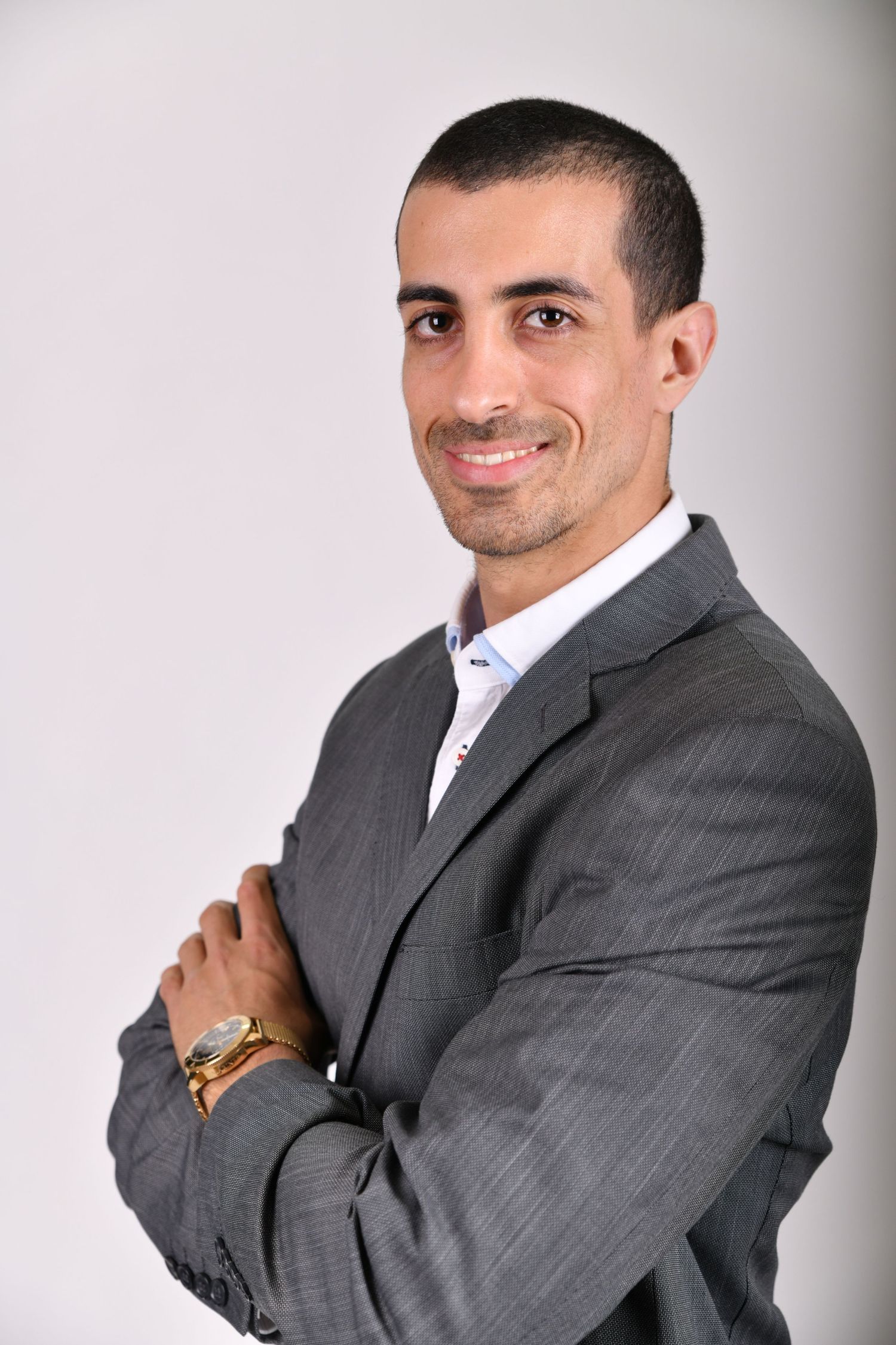 Professional portrait of a person in a gray suit smiling and posing against a light background.