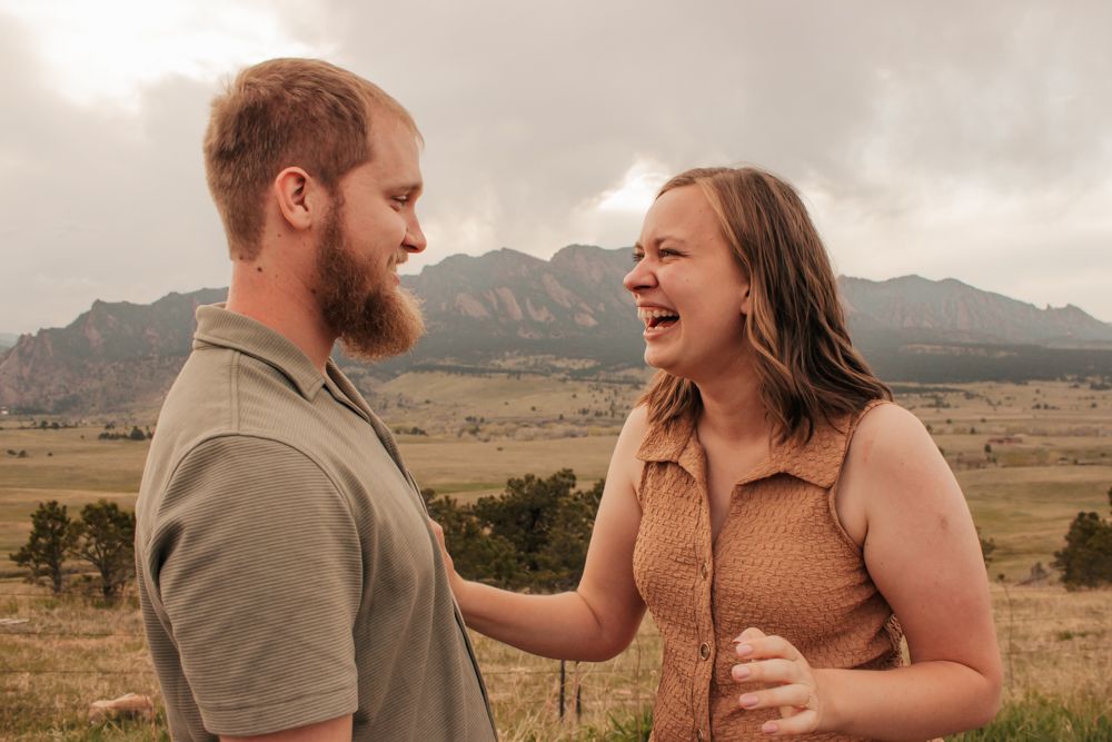 Couple laughing together in a Colorado field with the Flatirons in the background | What to Wear for Family Photos