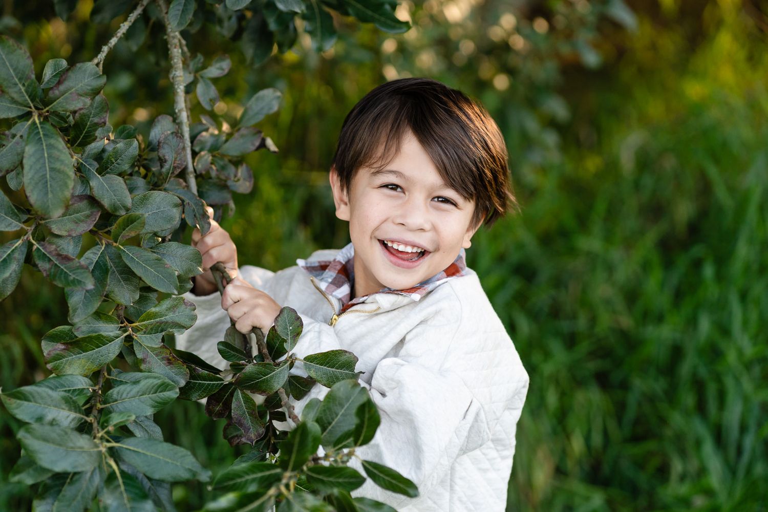 Boy smiling by a tree.